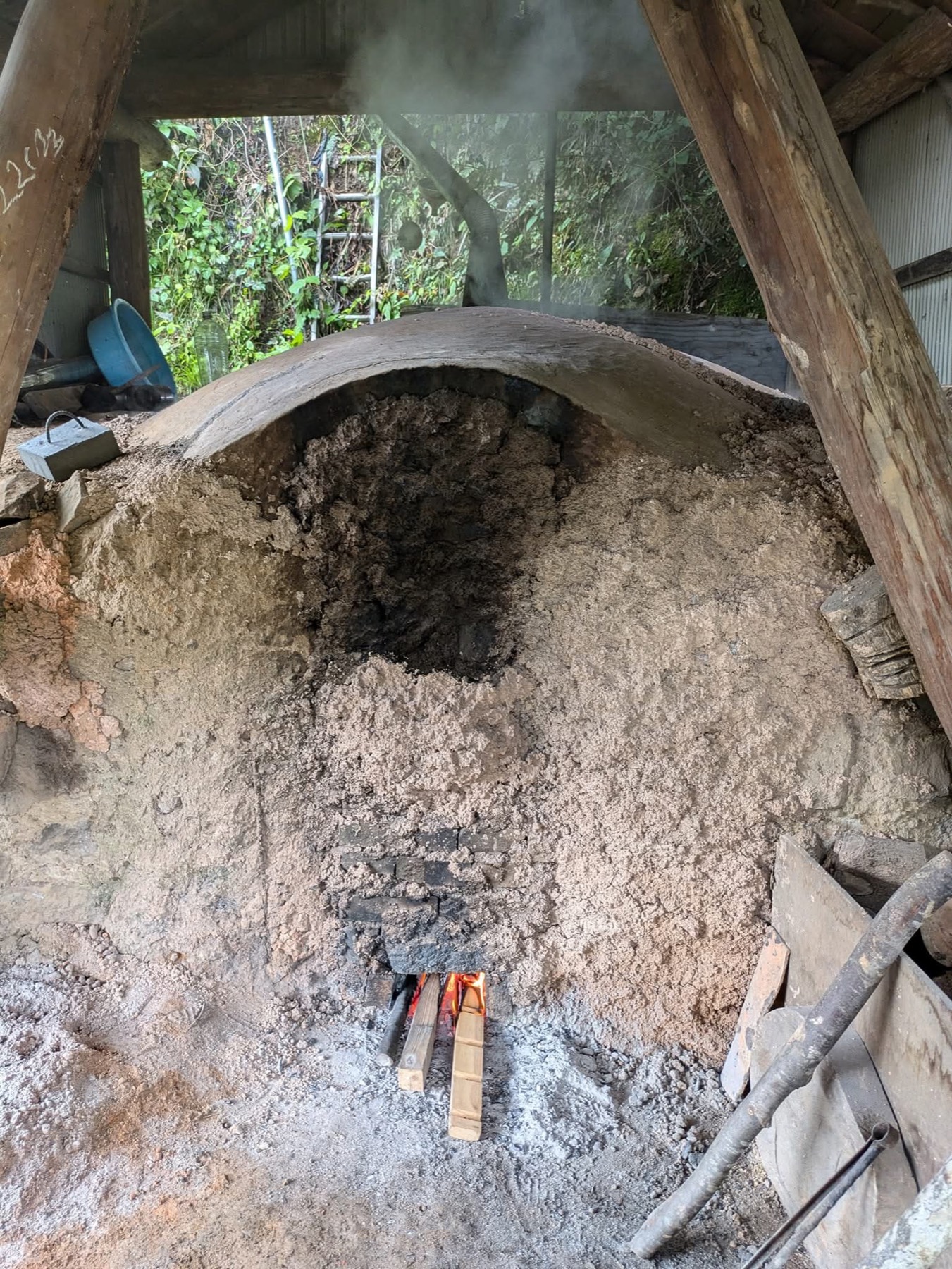 煙をあげながら炭化が進む、富山県朝日町笹川の炭焼き土窯
