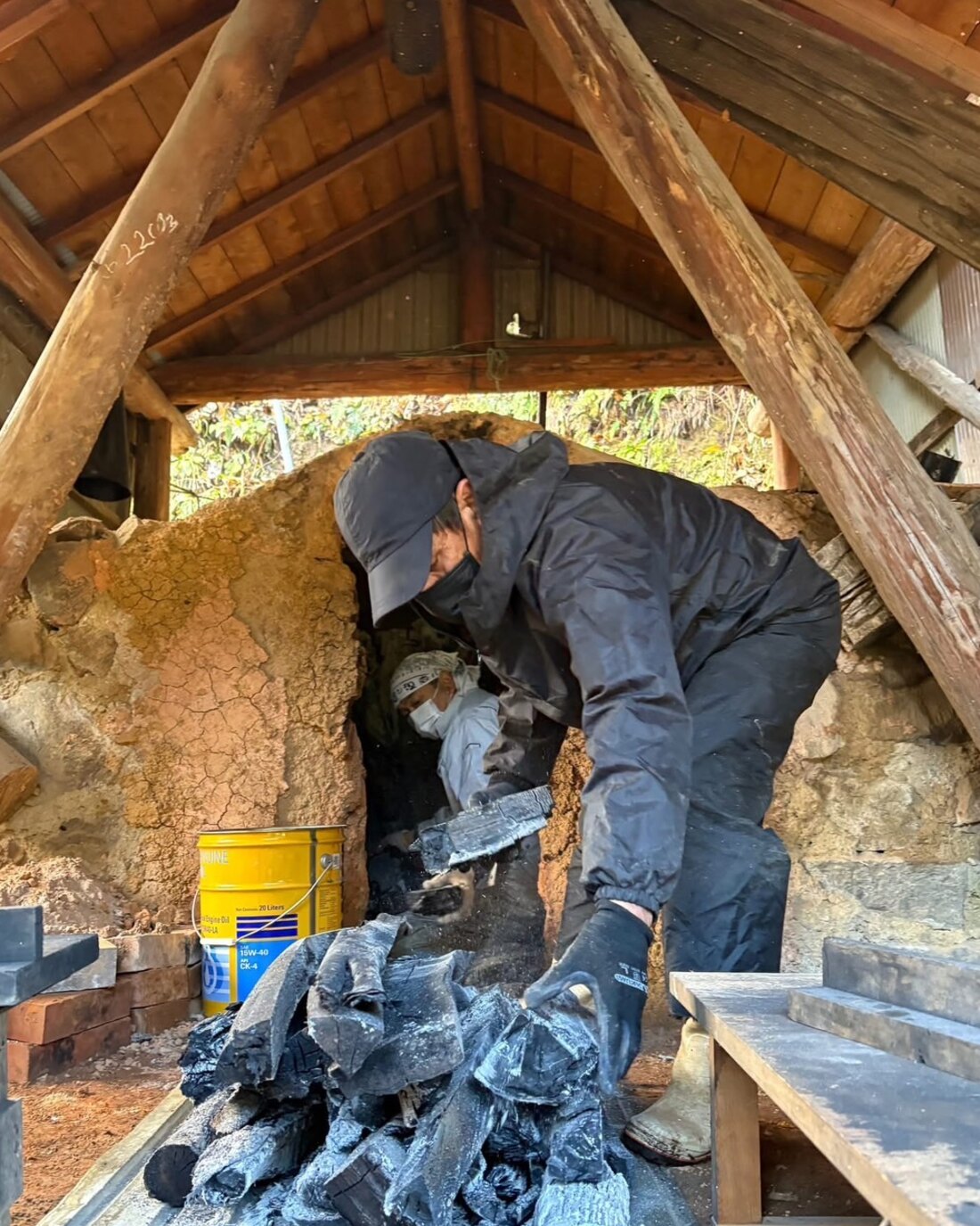 窯出しの日、土窯から炭を運び出す竹内伸さんと折谷孝良さん（富山県朝日町笹川）